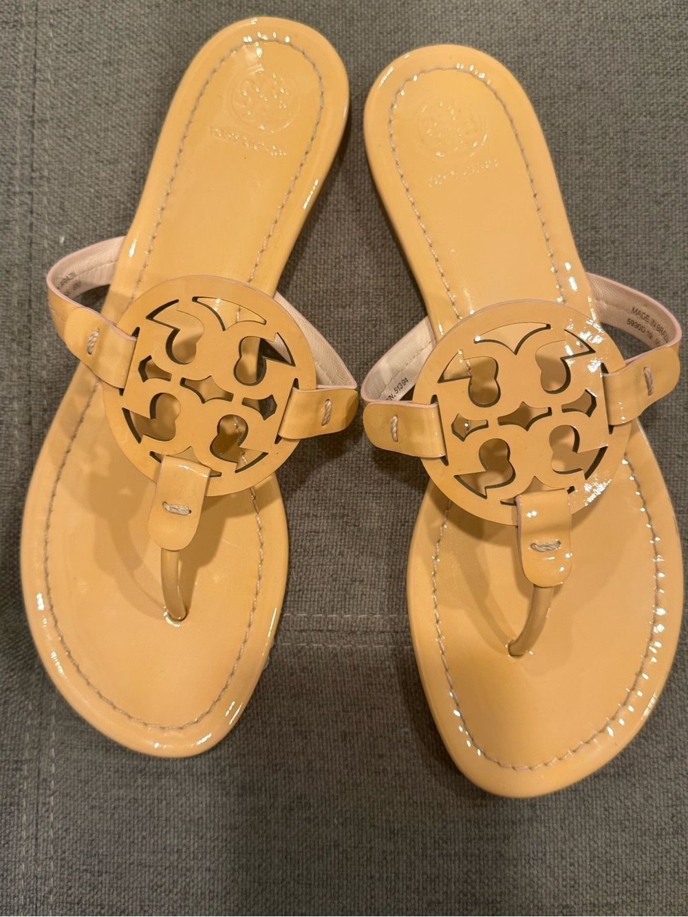 Tory Burch Patent Leather Thong Sandals  color is a pinky peach nude color.
